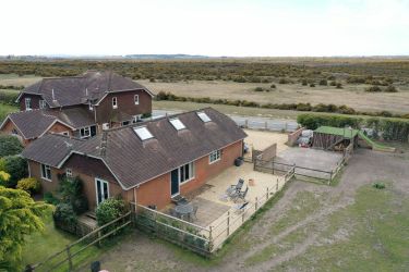 Aerial view of East Boldre Bartley Barn and terrace with forest behind, Isle of Wight in distance