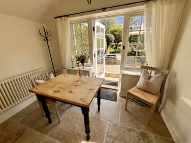 Sun room with dining table and chairs leading to downstairs cloakroom and garden.
