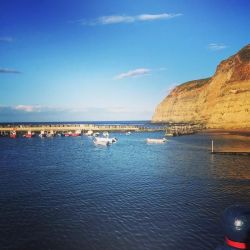 The towering, craggy cliffs and the peaceful harbour in Staithes