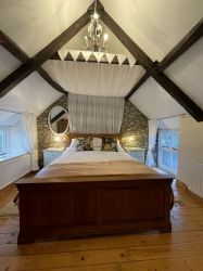 Romantic canopied king-size bed under 17th century beams, both windows have blackout blinds.