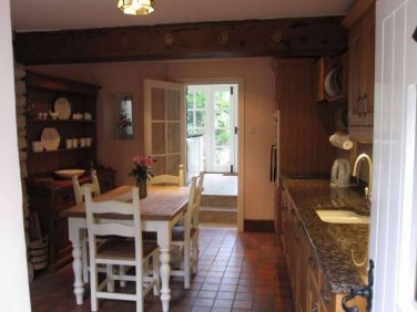 Kitchen showing utility room beyond and access to small garden
