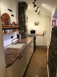 Galley kitchen with radiator, modern fittings, stone wall features
