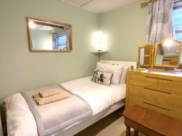 Twin beds in second bedroom with oak dresser and dimmable lights