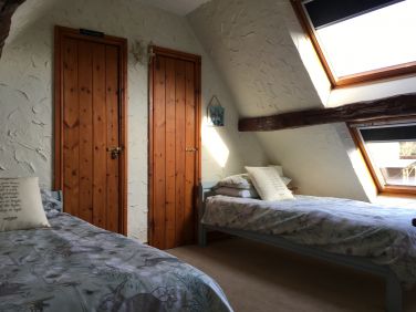 Attic bedroom with views over the back garden and meadows.