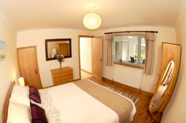 Bedroom with king size bed and large window overlooking the garden and countryside view