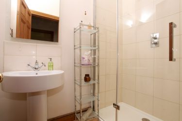 This smart new bathroom, with a large walk-in shower, is fully tiled with glass and chrome fittings.