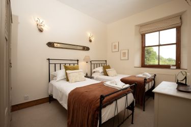 With views across the garden, bedroom four is a comfortable twin-bedded room in rich autumn colours.