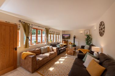 Cosy sitting room with leather sofas and wood burner
