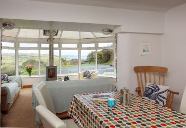 Dining area in conservatory with wood burning stove and sea views