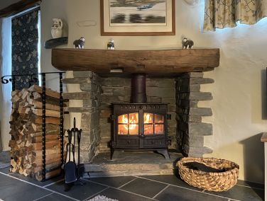 Wood burner lit with plenty of logs. Swill baskets (right) used to be made here