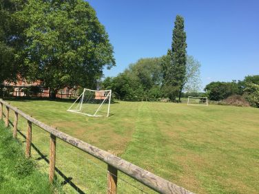 Huge playing field with football goals.   Many a football, rounders or cricket match has taken place