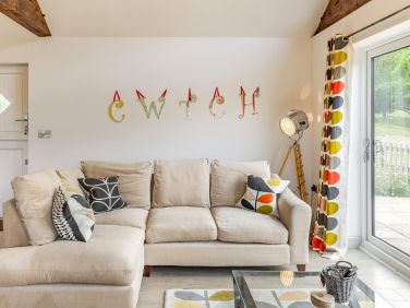 Spacious living area with feature oak beams and garden access at Cwtch