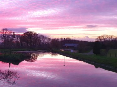 Sunset reflecting on pond in front of the Cwtch