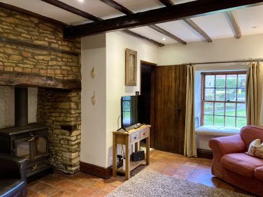 Bakers cottage sitting room with log burner in inglenook fireplace