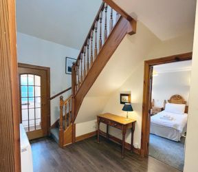Downstairs hallway with wood effect flooring and stairs to upstairs bedrooms and bathrooms.