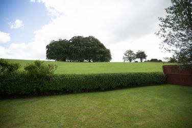 Wall & Lakes holiday cottage, countryside retreat, rolling green lawns and fields behind.