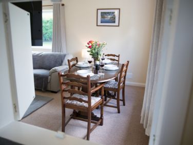 Serving hatch into the dinning area with solid wooden table and chairs.