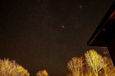 A magical starry night, clear skies above and peaceful countryside glowing under the stars.