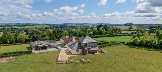 Aerial view of Higher Kellacott and The Cottage, with surrounding woodland and field views