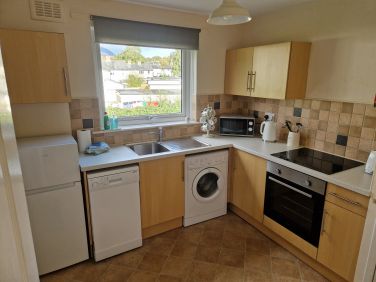Modern kitchen with dishwasher and washing machine/dryer.