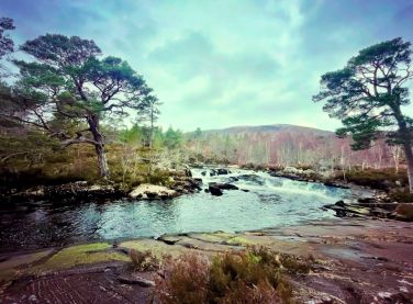The River Affric from the car park at twilight as the sun and light fade behind the mountains.