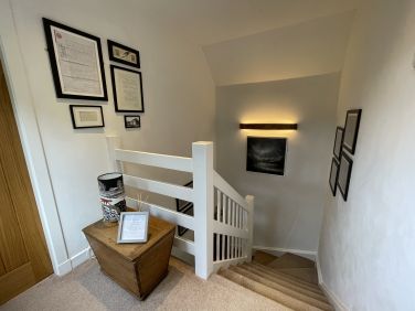 Historical documents and estate plans line the stairway, showcasing the local heritage on the walls.