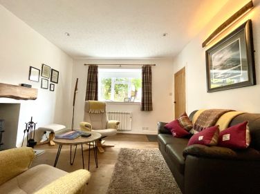 A cosy lounge featuring a log burner, two-seater sofa, and comfortable reclining chairs for relaxing