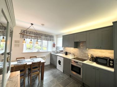 A shaker kitchen featuring a hob, oven, dishwasher, washing machine, and a large fridge/freezer.
