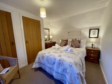 A double bedroom featuring a classic country throw and scenic views across the surrounding valley.