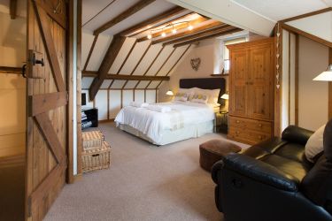 Large spacious adults bedroom with comfy sofa and TV