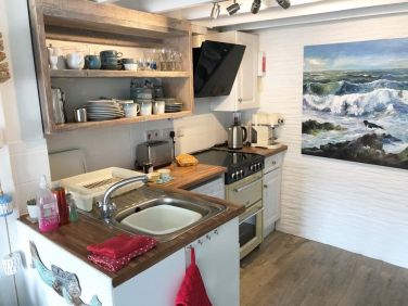 A retro cooker, beautiful sea painting and reclaimed wooden shelves, for a relaxed period feel.