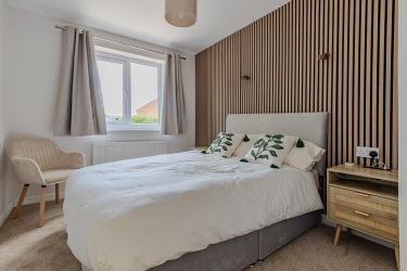 Bedroom one featuring double bed, acoustic wall panelling, bedside tables and lamps with dressing ta