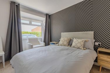 Bedroom one with double bed, bedside cabinets, bedside lamps, and bay window