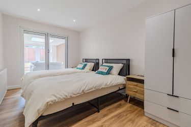 Bedroom 3 with twin single beds, wardrobe, laminate flooring, and bedside cabinets.