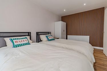Bedroom 3 featuring acoustic wall panelling, twin single beds, wardrobe, LED lighting, and laminate