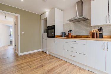 Fitted kitchen featuring built-in oven, hob, extractor fan, washing machine, and built-in dishwasher
