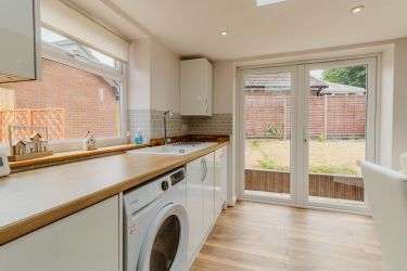 Fitted kitchen featuring built-in oven, hob, extractor fan, washing machine, and built-in dishwasher