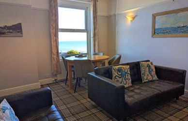 The living room with dining table in the window looking out over the sea
