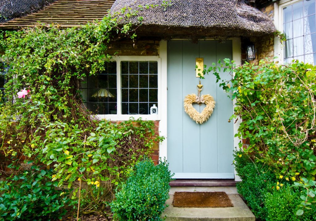 Blue cottage front door with rustic heart and thatched roof over