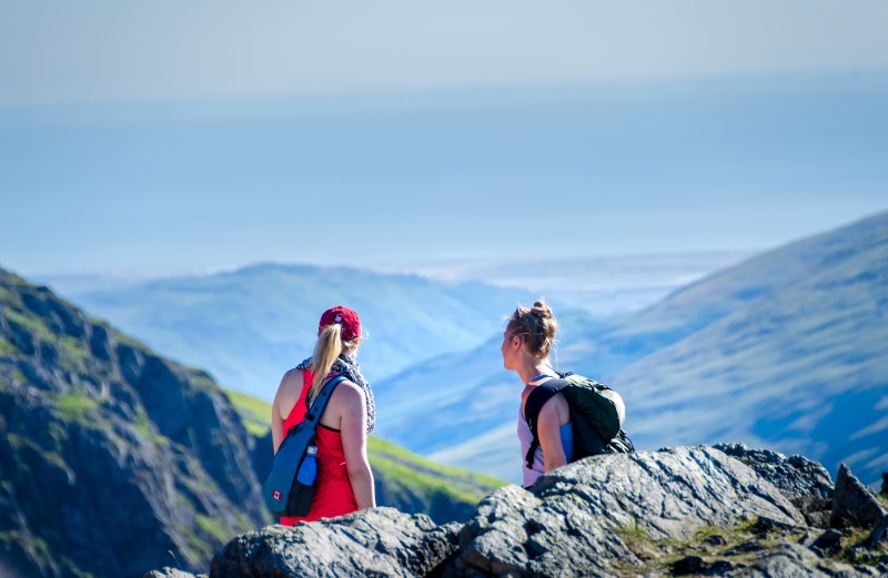 Two female hikers with backpacks looking at the mountain views