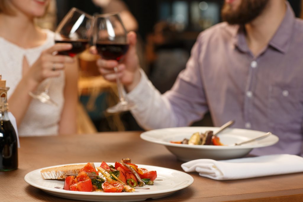 Couple toasting a glass of red wine over a meal