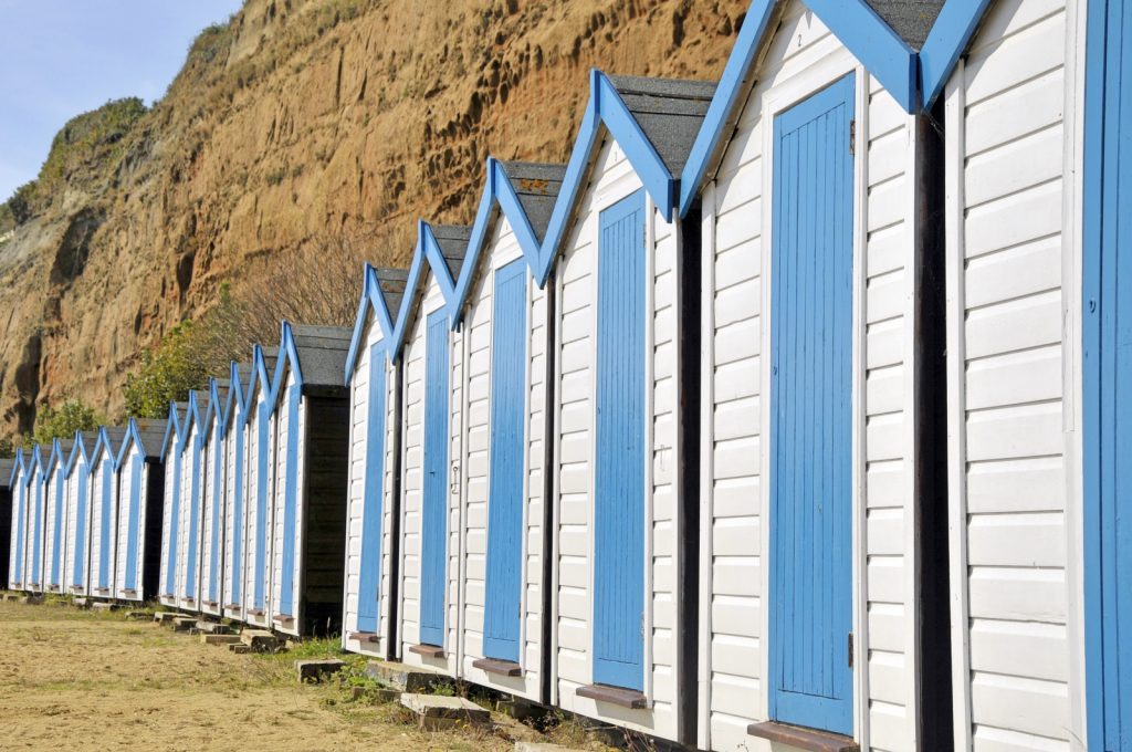 Row of blue and white beach huts against the cliffs