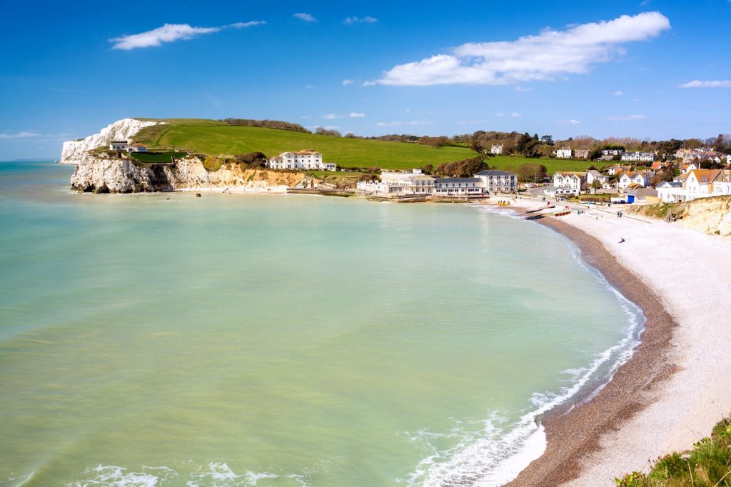 Turquoise waters against the white beach of Freshwater Bay, fringed by white cliffs and rolling countryside 