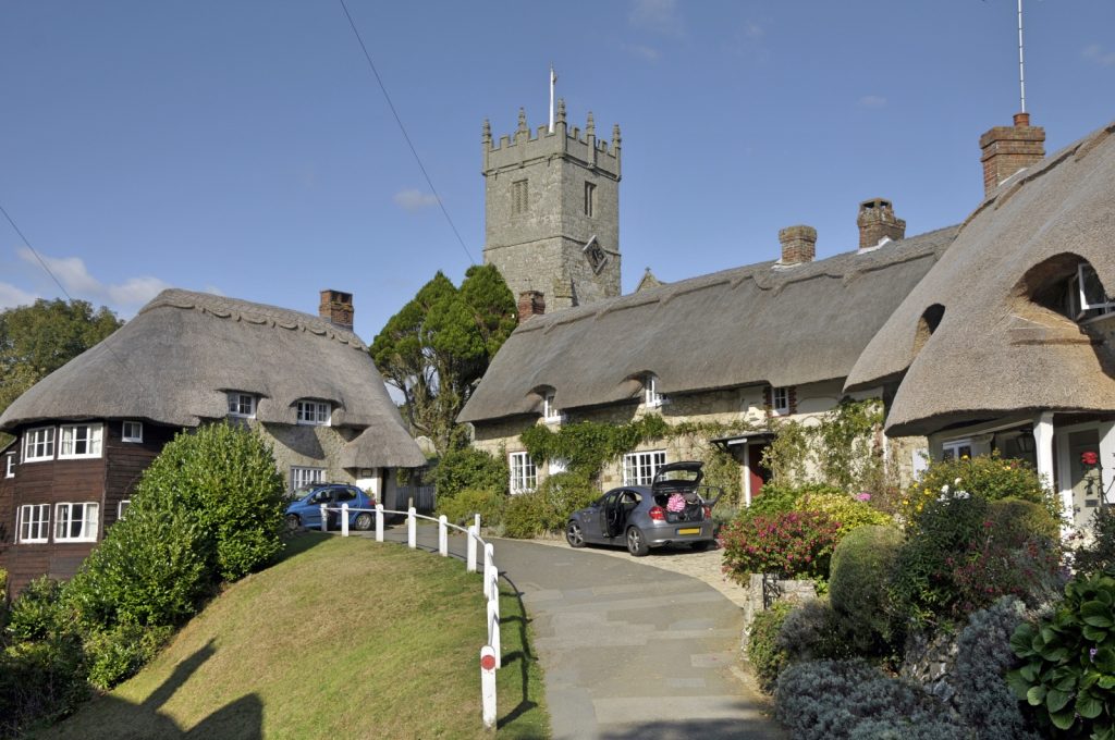 Picture of a village lane with thatched cottages and church steeple