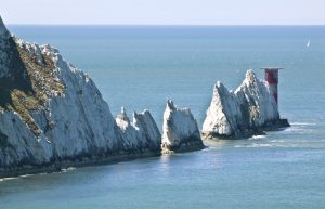 White chalk Needles jutting out of the sea with a red and white light house on the end