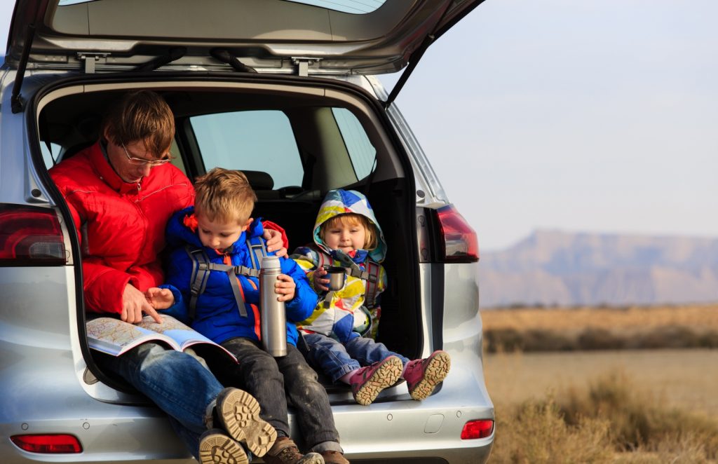 Dad showing a child the map sitting in the boot of car