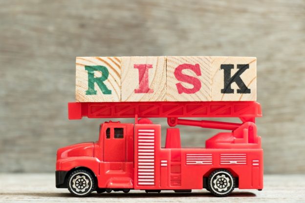 A red toy fire engine with blocks on roof saying 'risk'