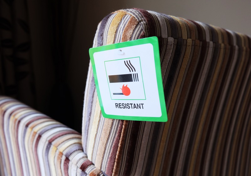 Armchair with fire resistant label on it showing a cigarette with match underneath