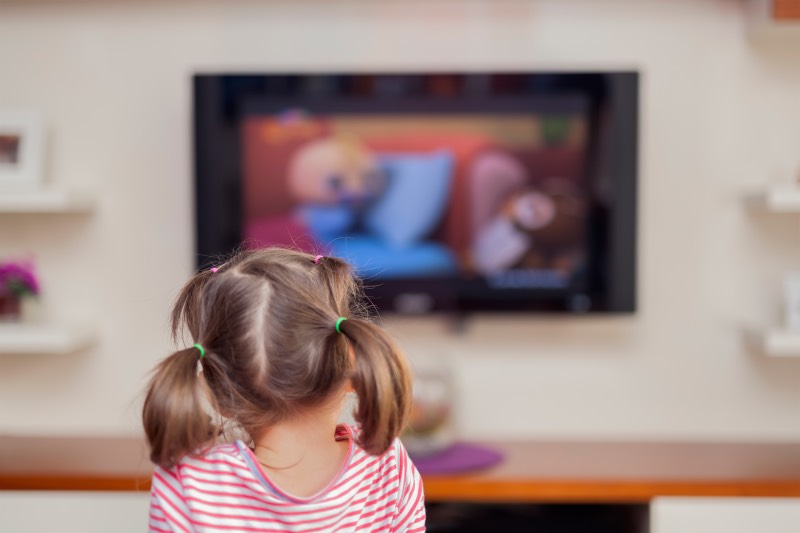 Little girl sitting in front of television