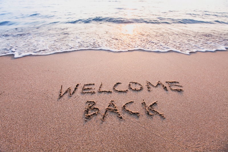 Welcome Back written on the beach in sand